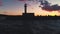 Lighthouse and sea at sunset. Sailing cargo ship near harbour