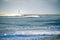 Lighthouse in the sea during windstorm with seagulls. blue sky a