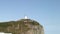 Lighthouse seamark on green stony rocks coastline beach in Japan Sea.