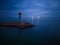 lighthouse on the seashore with red light at night against the background of the lights of the ships