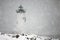 Lighthouse Shines Green Light During Snowstorm