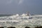 Lighthouse shrouded in waves during a storm in the Mediterranean.