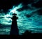 Lighthouse silhouette against ominous sky.