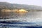 Lighthouse on the small island in front of big mountains and blue sea surface in the front