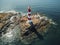 Lighthouse on small island in the sea at sunny day in summer. Aerial top view of beautiful lighthouse on the rock, clear azure