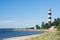 The lighthouse stands near the sea in summer