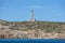 Lighthouse, stone and concrete beacon on hill at Ermoupolis port, Syros island, Greece