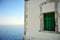 Lighthouse wall with green window, blue sky and sea