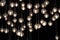 Lighting balls on the chandelier in the lamplight, light bulbs hanging from the ceiling, lamps on the dark background, selective