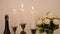 Lighting candles on the Chandelier, three candles on a romantic table next to flowers and wine. Blowing out