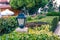 Lighting ground lamp street mounted on a green lawn in a park with plants and a winding curved footpath