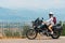 A lightly dressed girl is sitting on a motorcycle. No protection. Helmet. Sunny day in Narni, Italy. Green mountains in the