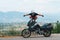 A lightly dressed man and his adventure motorcycle. No protection, only helmet. Sunny day in Narni, Italy. Green mountains in the