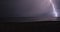 Lightning bolt lights up the sky on beach at night during a storm