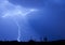 Lightning bolt thunderstorm in a blue sky and silhouettes of cacti in North Scottsdale, Arizona