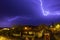 Lightning cracking during thunderstorm over houses of tiny town