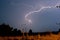 Lightning fast on a stormy summer night. A field with poles and electric wires