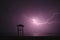 Lightning flashes across the night sky on beach. Violet color. Weather concept in resort areas