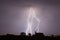 Lightning in a slow moving thunderstorm over trees.