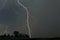 Lightning in a slow moving thunderstorm over trees.