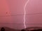 Lightning strike, rainbow and red tones skies in a stormy afternoon