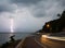 lightning thunderbolt in sea at twilight with lighting from cars