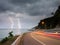 Lightning thunderbolt in sea at twilight with lighting from cars