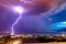 Lightnings striking on the ocean from gloomy skies at night framed with coastal buildings