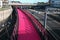 Lightpath over freeway. Urban walkway in pink color for bicycle riders. Nelson Street Cycleway over highway, Auckland, New Zealand