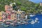 Liguria Portofino View of harbor with moored boats and pastel colored houses lining the bay with trees on hills behind, Italy