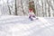 A liitle child rides an iceboat in a snow-covered forest. A little girl sitting on her ass slides down a snow slide. Concept of
