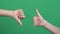 Like dislike gestures. Two hands showing different signs thumbs up and thumbs down over green screen background.