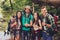 We like it! Four excited friends are gesturing like signs, posing for portrait in a sunny summer jungle wood, smiling, bonding. Ha