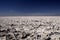 Like on the moon: View over endless bright white barren salt plateau into the nowhere contrasting with deep blue sky