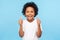 Like! Portrait of happy little boy with curly hair in white T-shirt smiling at camera and doing thumbs up gesture