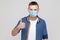 Like. Portrait of satisfied young man in casual style with surgical medical mask standing, thumbs up and looking at camera. health