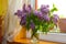 Lilac bouquet of flowers on a wooden window. cozy floral decor in room
