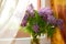 Lilac bouquet of flowers on a wooden window. cozy floral decor in room