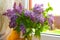 Lilac bouquet of flowers on a wooden window. cozy floral decor in room