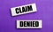 On a lilac bright background, light wooden blocks with the text CLAIM DENIED