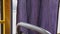 The lilac curtain oscillates near glass of bus. A purple curtain flutters