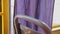 Lilac curtain oscillates near glass of regular bus. Purple curtain flutters