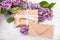 Lilac flowres, gift box and envelope on white wooden background.