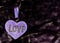 A lilac heart with the inscription love on an blurred dark background