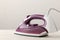 lilac iron on a light background. ironing clothes. household electrical appliances