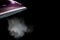 Lilac iron releases steam on a black background. ironing clothes. household electrical appliances. with space for text