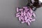 Lilac medical pills are falling out of a bottle on a gray background. Concept of health, drug addiction