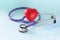 Lilac stethoscope and red toy heart with protective medical mask closeup