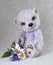 Lilac teddy-bear with a bunch of flowers at feet