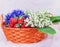 Lilies of the valley, strawberries and cornflowers in orange basket